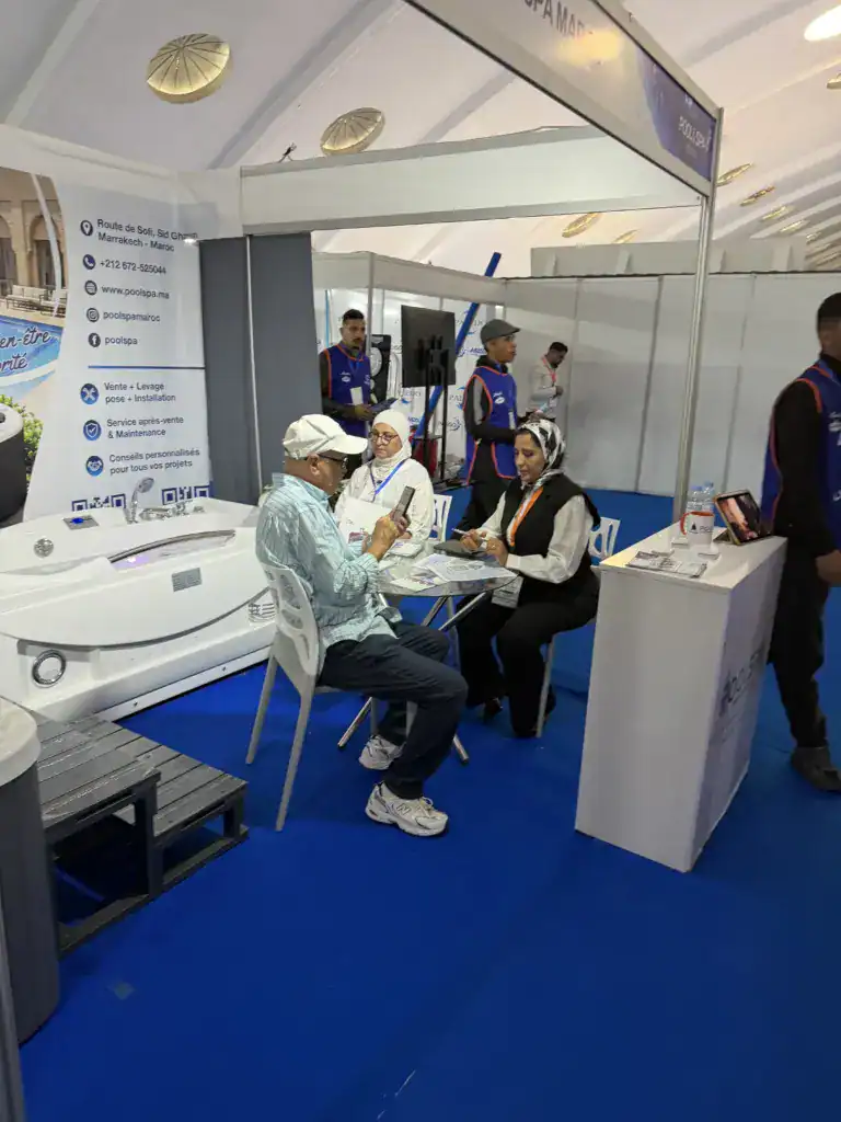 PoolSPA à Africa Pool & Spa Expo 2026 : le bien-être à la rencontre des professionnels 13 Trois personnes en discussion autour d’une table sur le stand PoolSPA, avec une baignoire de balnéothérapie à l’arrière.