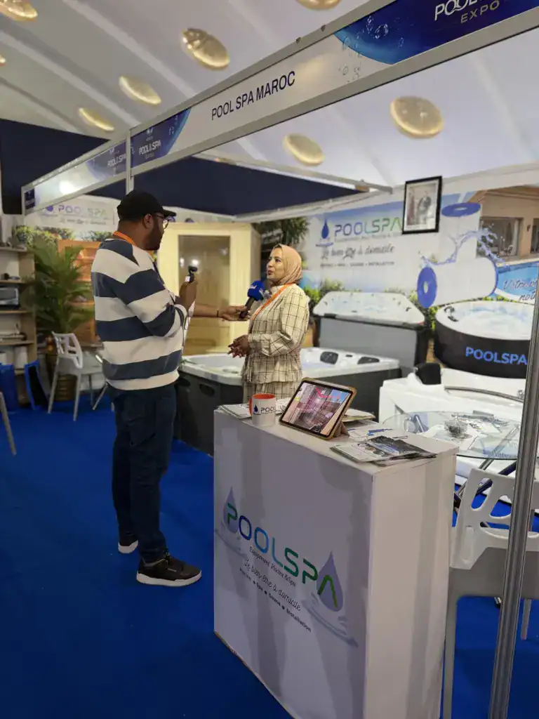 PoolSPA à Africa Pool & Spa Expo 2026 : le bien-être à la rencontre des professionnels 10 Homme tenant un micro lors d’une interview sur le stand PoolSPA, devant un spa et le comptoir de l’exposant.