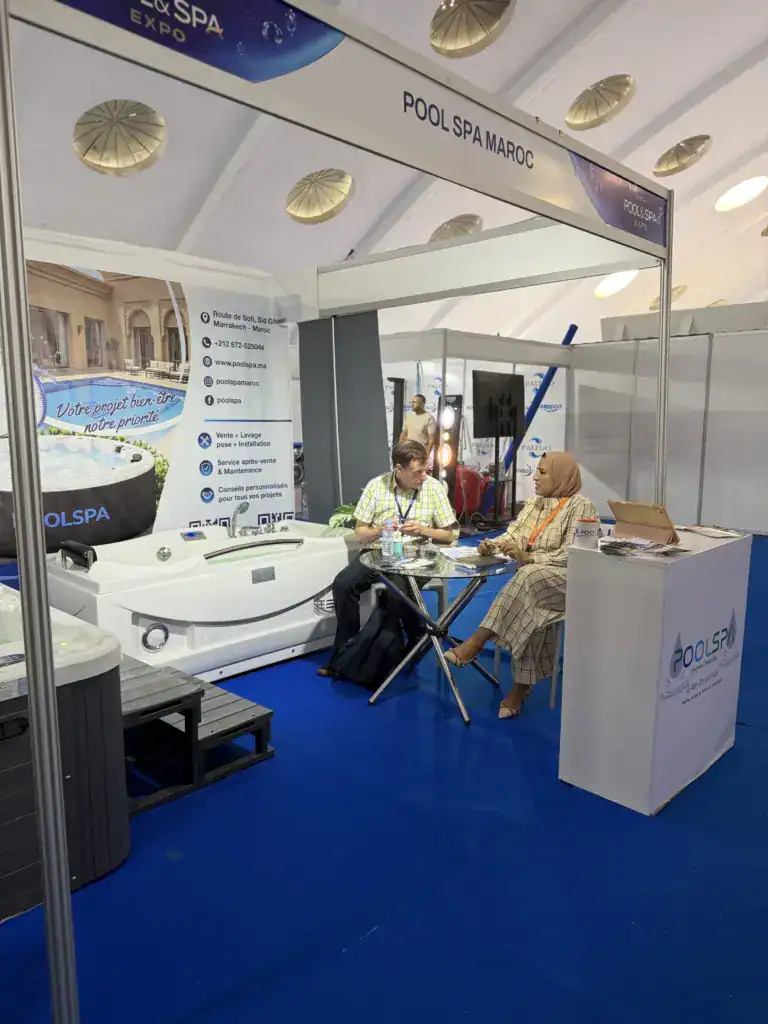 PoolSPA à Africa Pool & Spa Expo 2026 : le bien-être à la rencontre des professionnels 11 Visiteurs en discussion autour d’une table vitrée sur le stand PoolSPA, sous l’enseigne Pool Spa Maroc.